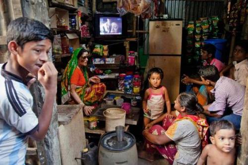 زاغه نشینان بنگلادشی دریک مغازه محلی تلویزیون تماشا می کنند (رویترز)
